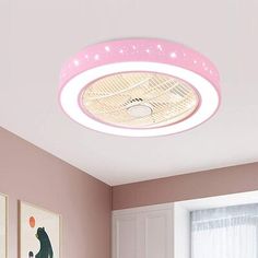 a bedroom with pink walls and pictures on the wall, including a round light fixture