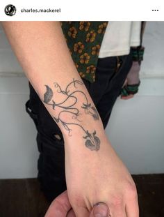 a person with a tattoo on their arm holding the hand of another person's wrist