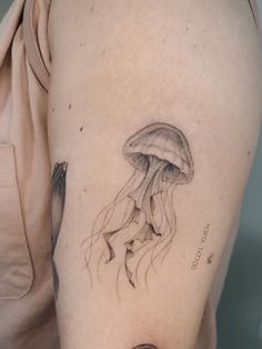 a woman's arm with a tattoo of a jellyfish on the left side