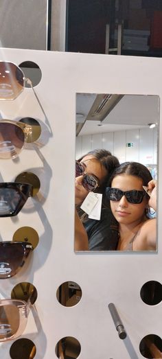 two women are looking in the mirror with sunglasses on display next to each other,