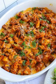 a casserole dish with meat and cheese in it on a table next to a salad