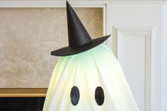 a white ghost with a black hat on it's head is sitting in front of a fireplace