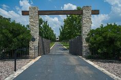 an entrance to a park with stone pillars and gated walkway leading into the park