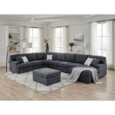 a living room with a large sectional couch and ottoman in the middle, along with a rug on the floor