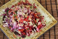 a bowl filled with coleslaw sitting on top of a bamboo place mat next to a spoon