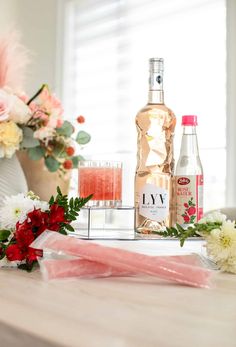 flowers and alcohol are sitting on the table next to each other in front of a bottle