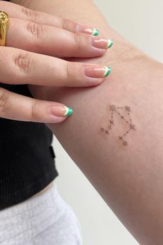 a woman with green and white nail polish on her left arm has a star tattoo