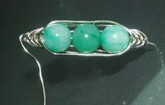 three green beads sitting on top of a piece of wire wrapped around it's ends