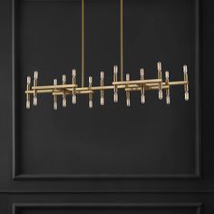 a large brass chandelier hanging from the ceiling in front of a black wall