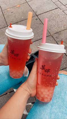 two people are holding cups with drinks in them