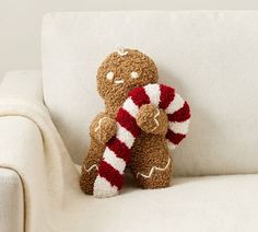 two teddy bears are sitting on the arm of a white couch, one is holding a candy cane