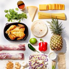 various foods are laid out on a white surface, including pineapples and other ingredients