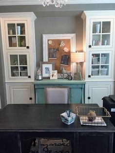 a desk with two baskets on it in front of some cupboards and a chandelier