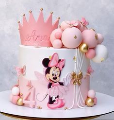 a pink and white cake with a minnie mouse design on the top is surrounded by balloons