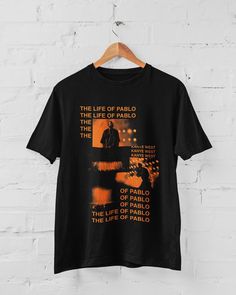 the life of pablo t - shirt on a hanger against a white brick wall