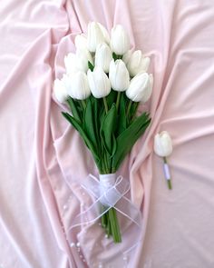 a bouquet of white tulips tied to a pink cloth