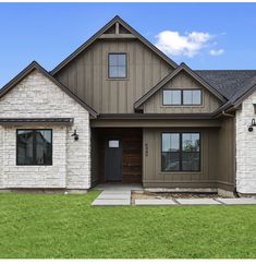 the front of a house with two story windows and brick sidings on each side