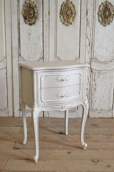 a white table with two drawers in front of wooden paneled walls and wood flooring