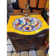 a bathroom sink with an artistic design on the top and bottom, surrounded by tiled walls