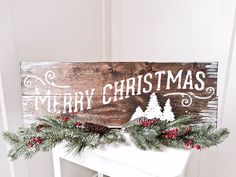 a wooden sign that says merry christmas with pine cones and red berries on the mantle