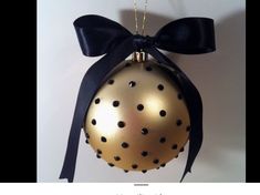 a gold ornament with black polka dots and a bow hanging on a wall