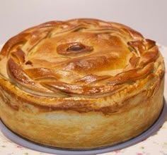 a baked pastry sitting on top of a white and pink tablecloth covered cake plate