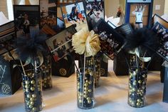 three vases filled with candies and photos on a white tablecloth covered table