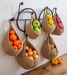 four bags hanging on the wall with fruits and vegetables in them