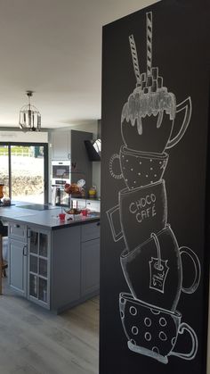 a chalkboard drawing of a coffee cup on the side of a wall in a kitchen