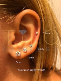 a woman's ear is shown with three small diamond studs on the side