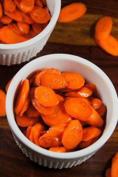 two white bowls filled with carrots on top of a wooden table