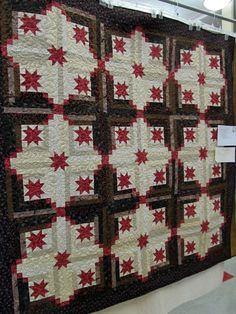 a quilted wall hanging on the side of a building with red and white stars