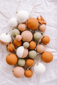 an arrangement of different colored ornaments on a white sheet with twine and string attached to them