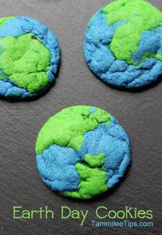 three cookies with green and blue icing on top of each cookie, one has the earth in it's center