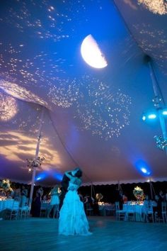 a couple is dancing under the stars in the sky at their wedding reception on the dance floor