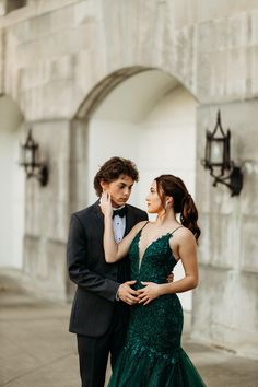 a man in a tuxedo standing next to a woman in a green dress