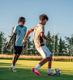 two young men are playing soccer on the field