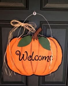 a welcome sign hanging from the front door with a pumpkin on it's side