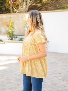 Introducing the Michelle Babydoll Top - Yellow, the perfect addition to your wardrobe! This top is designed with layers of the softest fabric and features patterns that will make you swoon. The flowy and fun design of this top ensures that you'll create a charming look in no time. Crafted with a babydoll fit, the Michelle top is designed to flatter your figure without overwhelming your overall look. Available in sizes Small (0-4), Medium (6-8), Large (10-12), and XL (12-14), you're sure to find Spring Breezy Tops With Floral Print, Breezy Flowy Spring Top, Breezy Flowy Top For Spring, Flowy Floral Print Top For Day Out, Flowy Breezy Tops For Day Out, Cute Flowy Tops For Spring, Flowy Short Sleeve Tops For Spring, Flowy Short Sleeve Breezy Top, Flowy Printed Cotton Tops