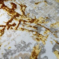 an area rug with gold and silver paint on it