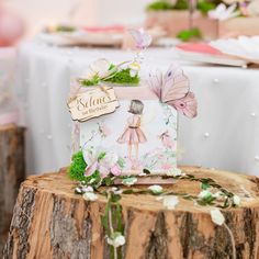 there is a small box on top of a tree stump with flowers and leaves around it