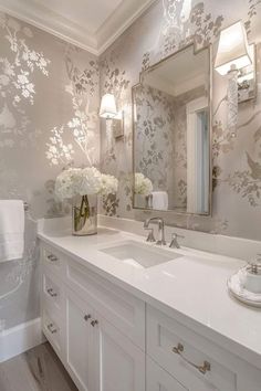 a bathroom with floral wallpaper and white cabinets