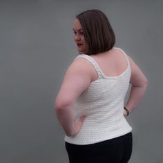 a woman in black pants and a white tank top with her hand on her hip