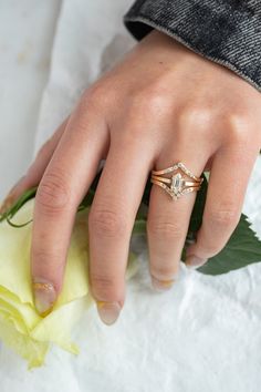 a woman's hand with a diamond ring on top of her finger and a yellow flower