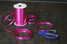 two spools of pink thread and scissors on a table with some other items