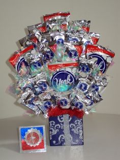 a vase filled with candy and candies on top of a white table next to a blue box