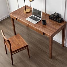 a laptop computer sitting on top of a wooden desk next to a chair and lamp