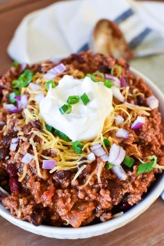 a white bowl filled with chili and sour cream