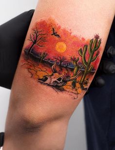 a person with a tattoo on their arm holding up a cactus and an orange sky