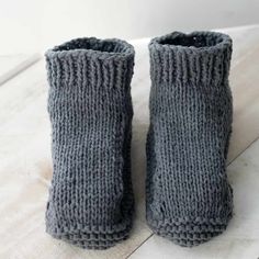 two gray knitted boots sitting on top of a white table next to each other